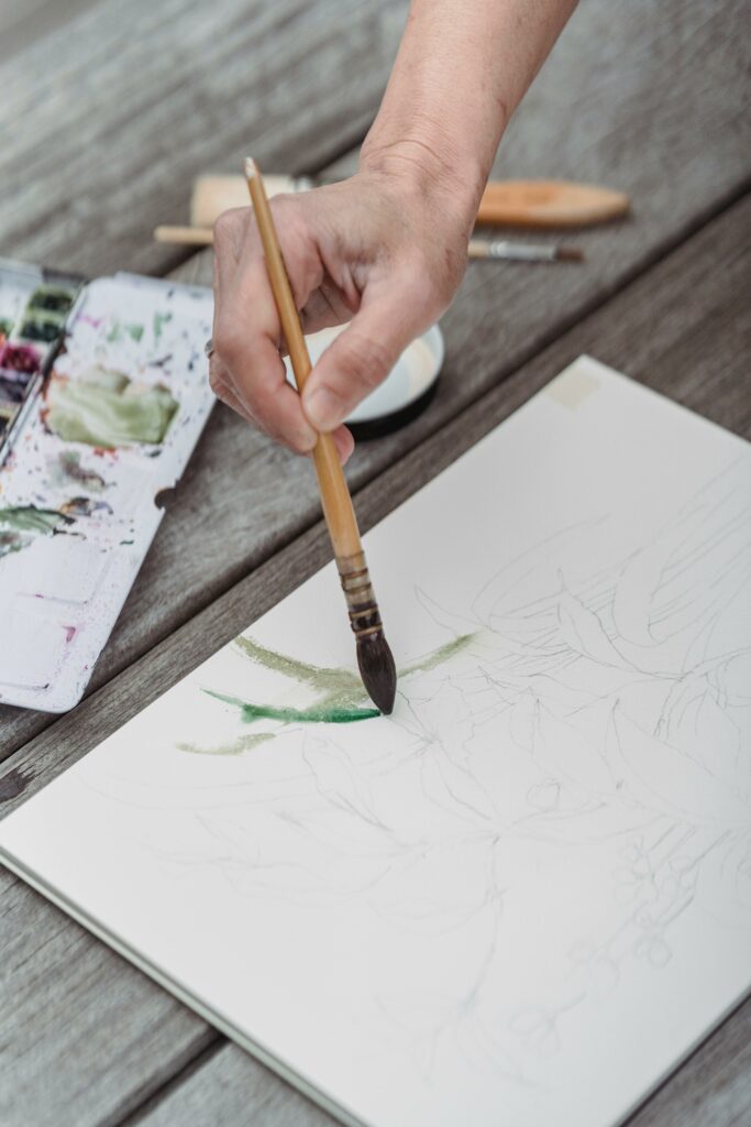 pexels-photo-7859168-7859168 A hand delicately paints with watercolors on a sketchpad, showcasing artistic expression.